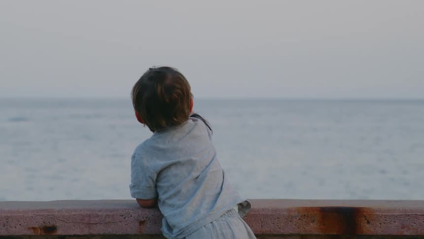 A boy points as waves in the ocean