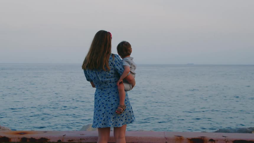A mother is holding her son on the beach