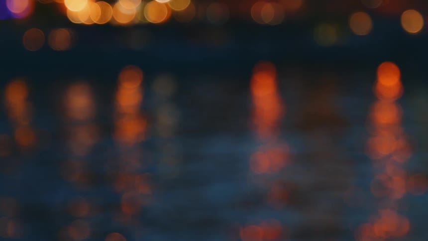 The surface of water reflecting light from the streets in the evening