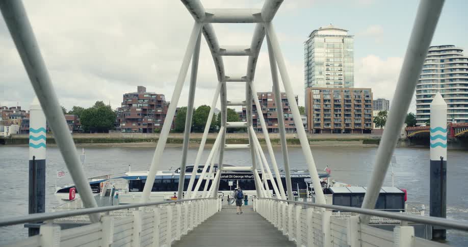 Man walks down a dock towards a boat on the River Thames