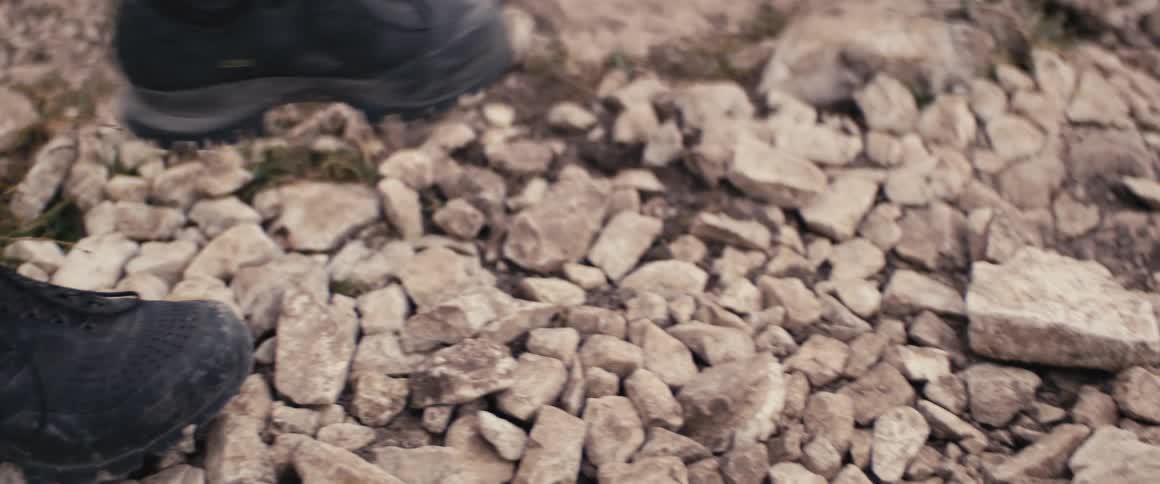 Close up of a persons feet wearing boots walking outside in nature during day time