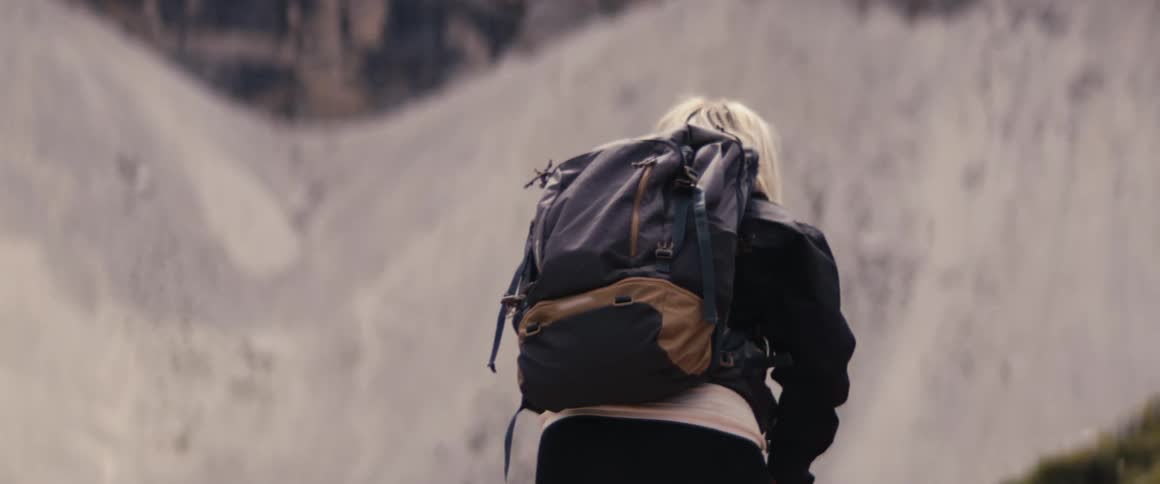 Woman carrying a backpack hiking on mountain peaks