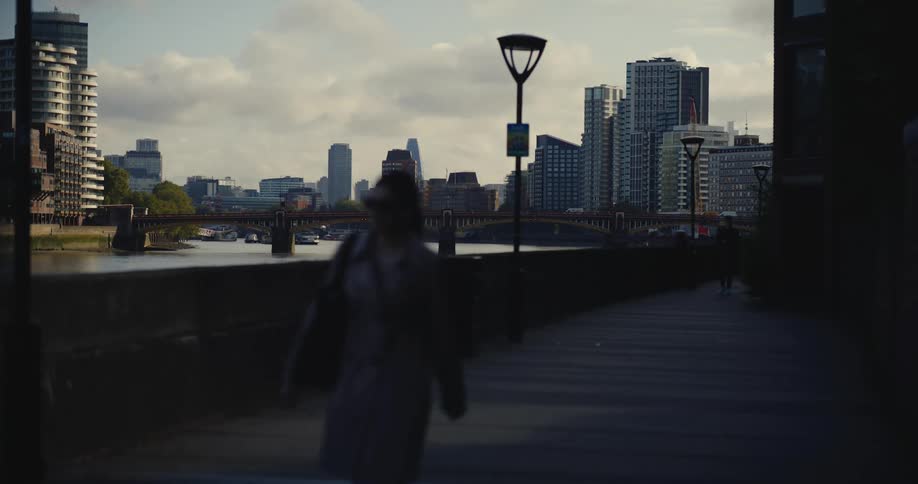 Woman walking along river thames with a view of the London skyline behind