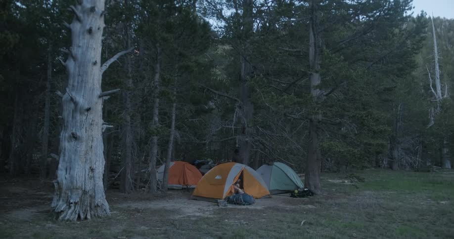 A camper is placing his backpack outside his tent early in the morning
