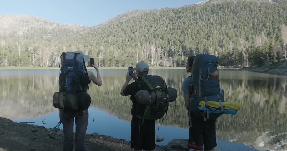 Hikers photograph a mountain lake