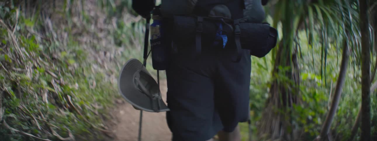 Person walking down a dirt path with two walking sticks