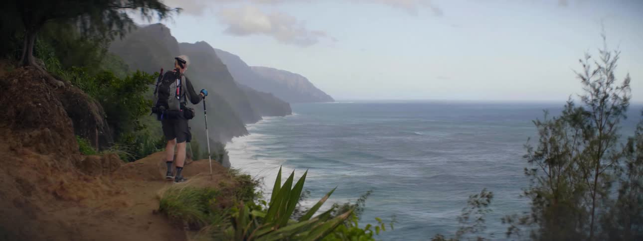 A man hikes to a cliff to look over the ocean