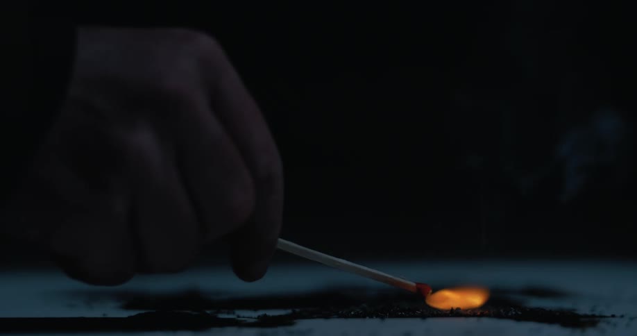 A person holds a flaring match and lights a surface