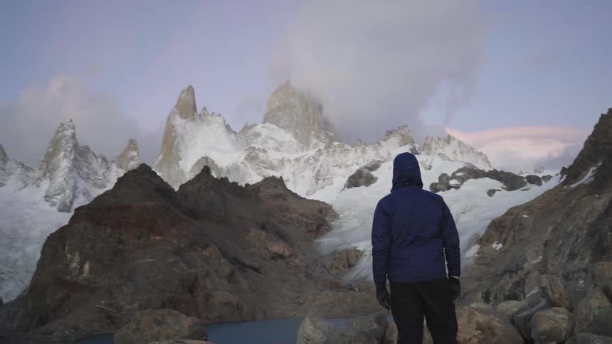 A hiker looks at a snowy mountain peak in the distance