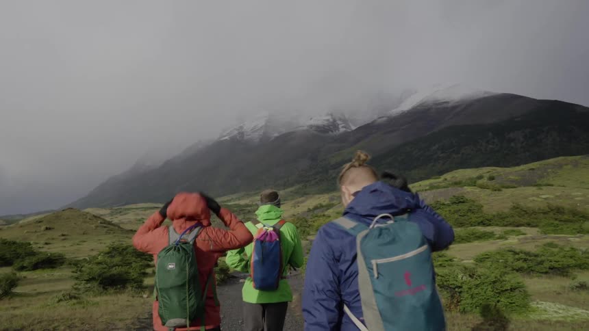 Hikers walk across an open area towards mountains in the distance