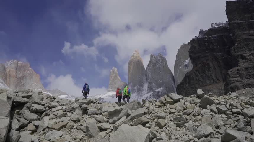 People hiking up rocky terrain in mountain wilderness in cloudy day