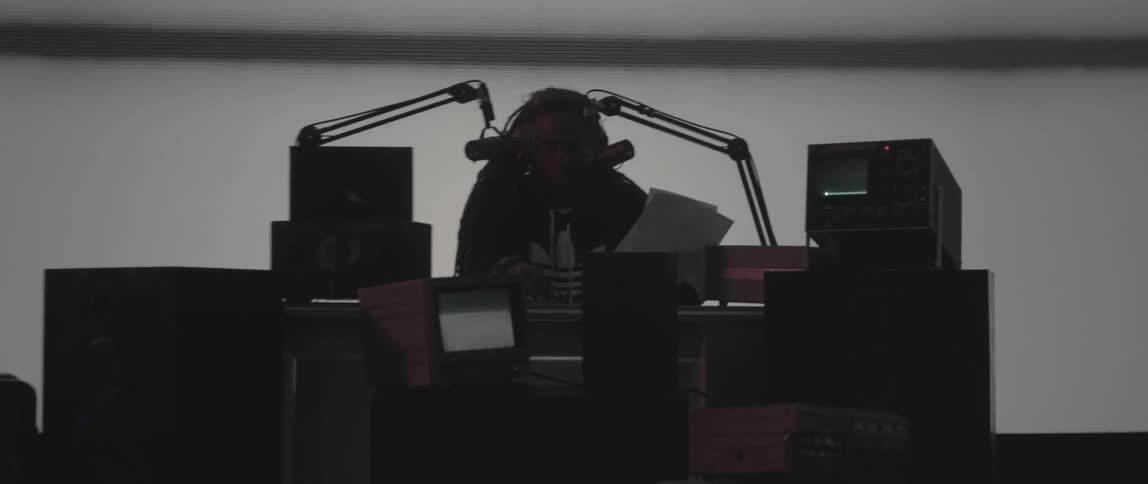 Man sits at a desk behind two microphones