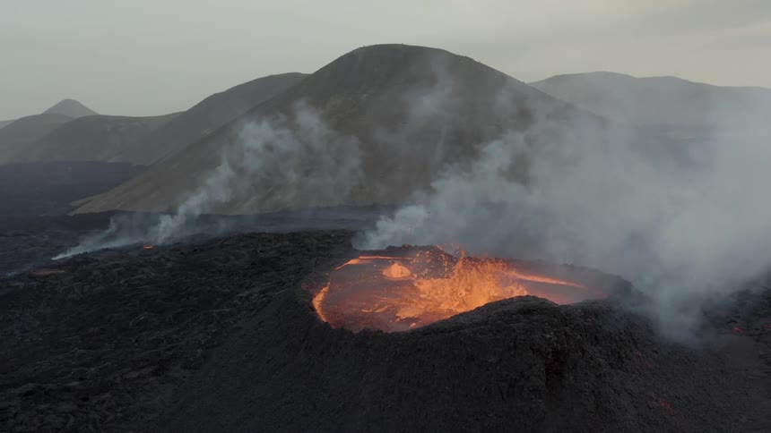 Molten hot lava splashes in an active volcano as smoke rises