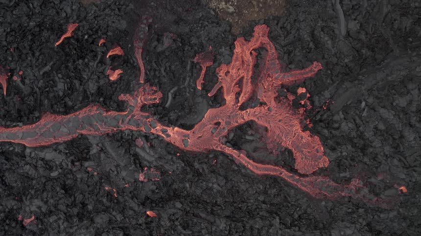 Lava flows across dark ash covered terrain