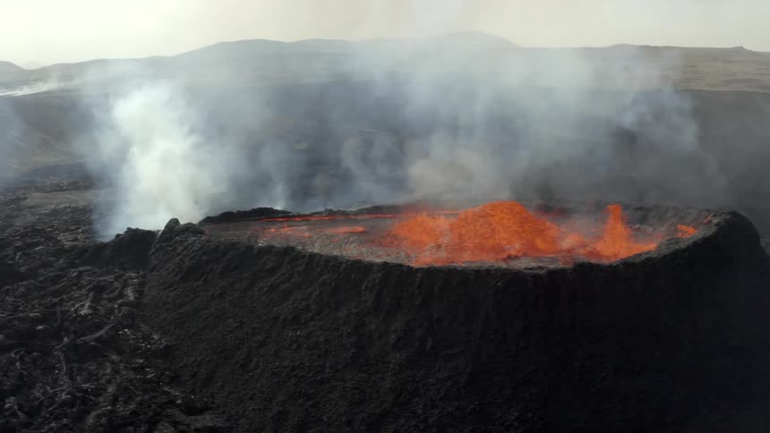 Aerial view of a volcanic crater spewing lava