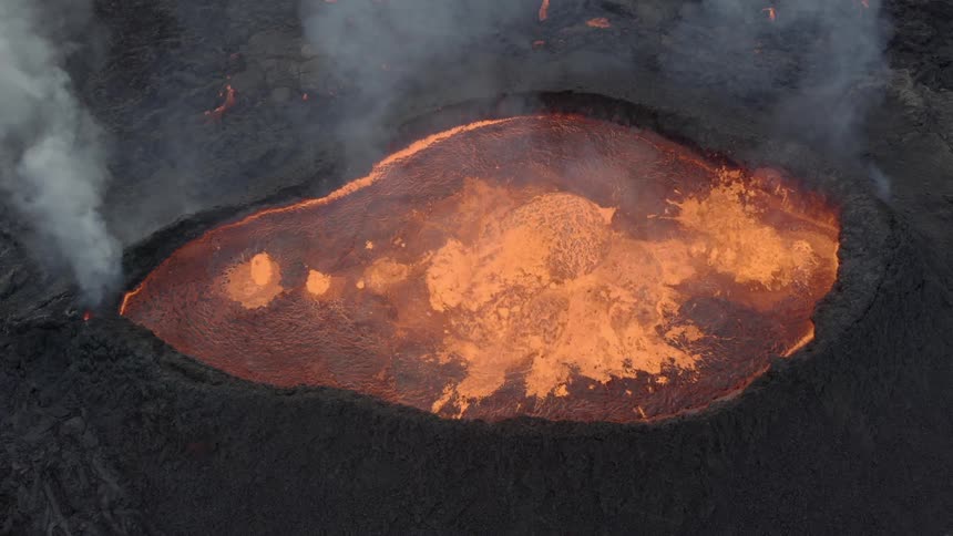Glowing molten lava splashes as magma rolls over the edge of an active volcano
