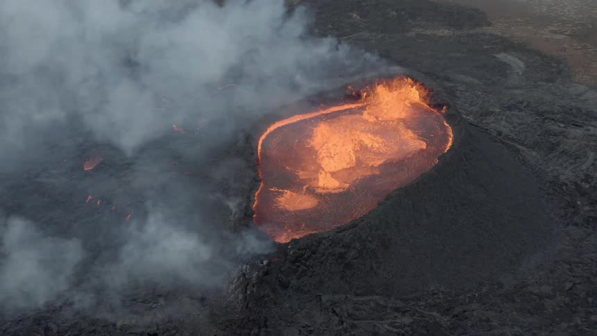 Aerial view of an erupting volcano with splashing lava and smoke