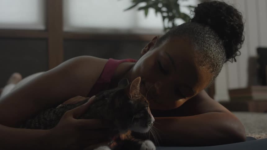 Woman lays on floor and pets cat