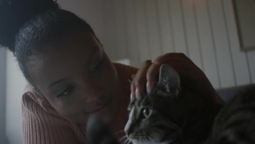 A girl smiles as she pets her cat