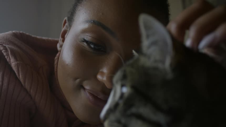 A young woman is petting a striped cat