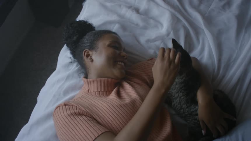 A woman lying in bed petting a cat