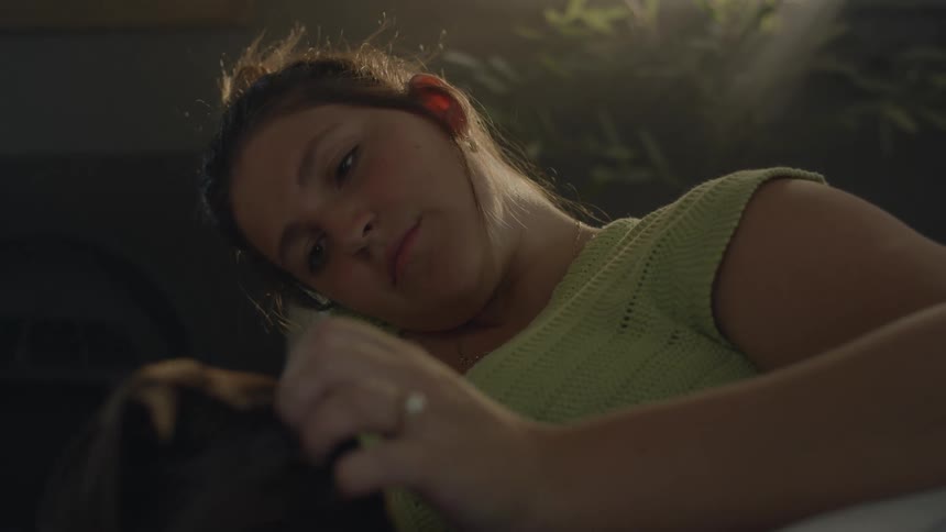 Closeup of a woman lying down with her dog petting and cuddling