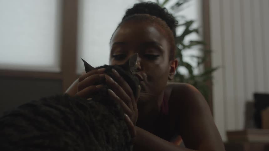 Woman pets and kiss cat near windows in home