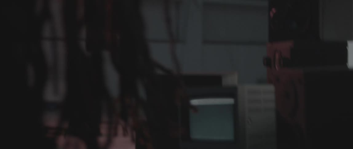 A person with dreadlocks adjusts a speaker