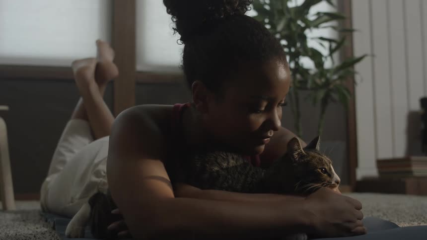 A woman lying down petting a striped cat