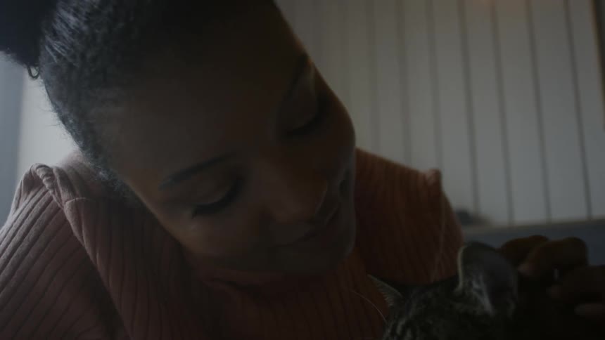 Young black woman caressing and giving a kiss to her cat