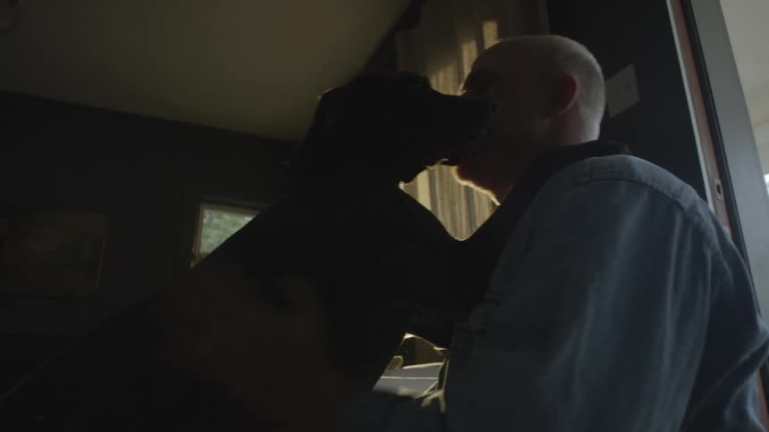 Man playing with his pet and the dog licks his face