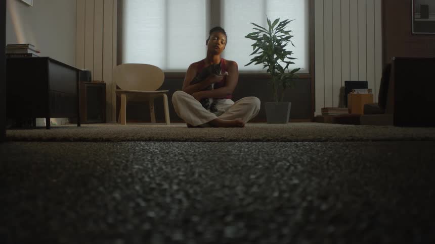 Woman sit cross legged on floor holding cat
