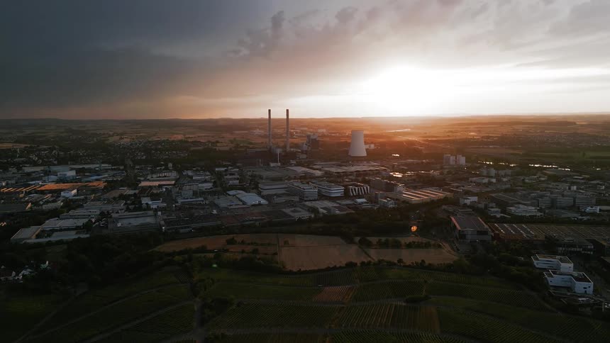 A residential area with power plants and in the background the horizon with the sunset