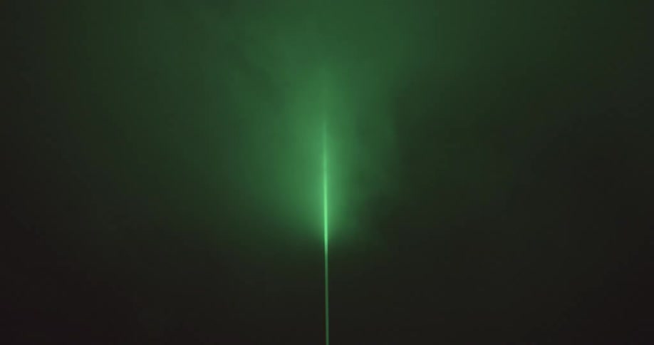 A green laser beam is in the fog fi