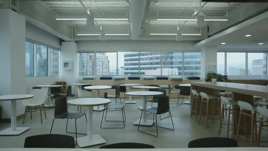 Tables and chairs in a large room with a view of downtown buildings