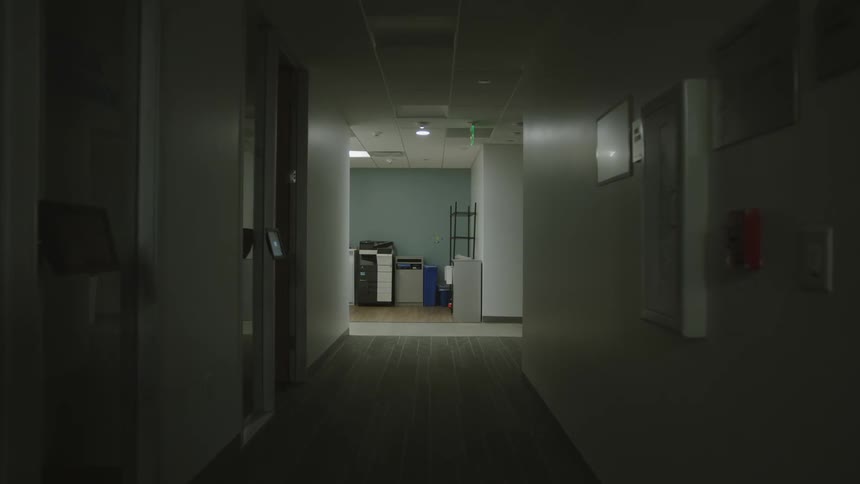 A corridor with several doors on the sides and white walls