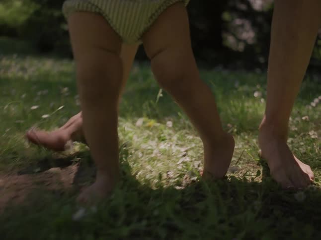 A parent is walking her baby in the grass