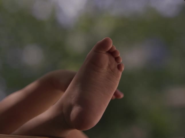 A baby playing with its hand and foot