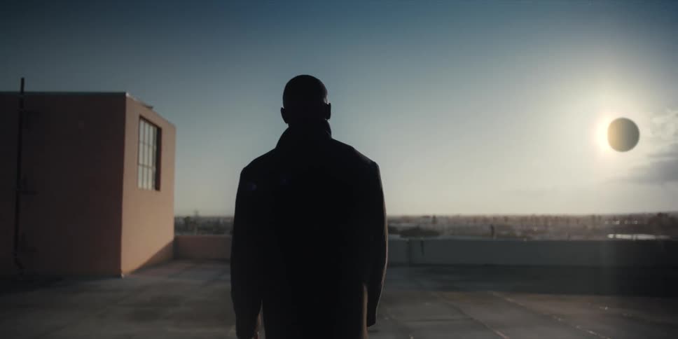 A man on a terrace watching a solar eclipse in the sky