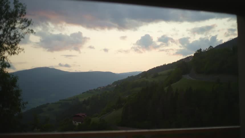View of a landscape with conifers houses and a mountain range during a sunrise
