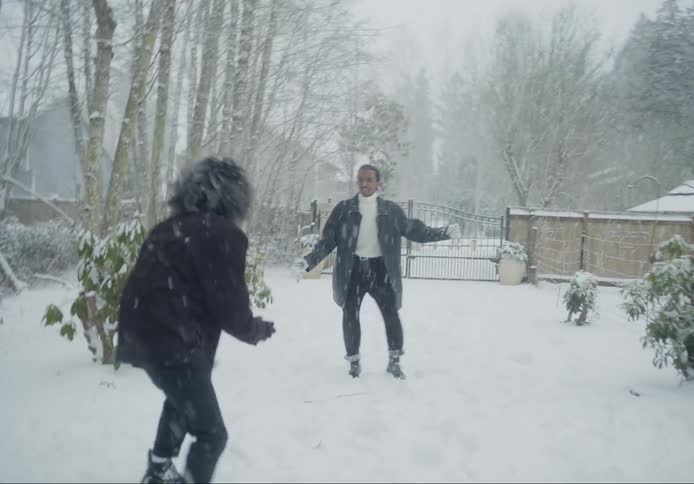 Two men playing with snowballs attacking each other while its snowing