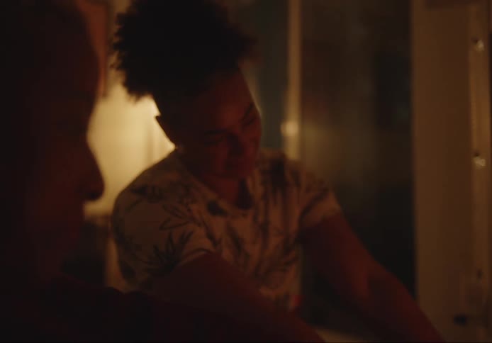 Two women warming their hands in a dimly lit environment with expressions of happiness