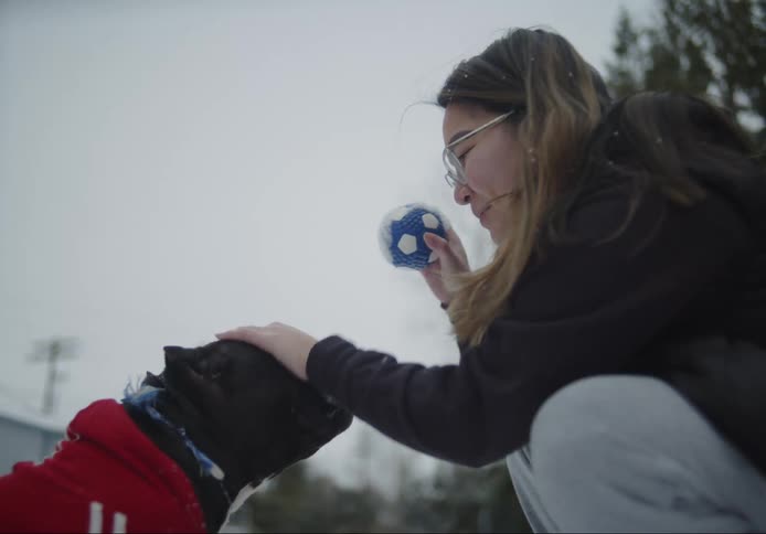 Woman pets her dog before playing catch in the backyard