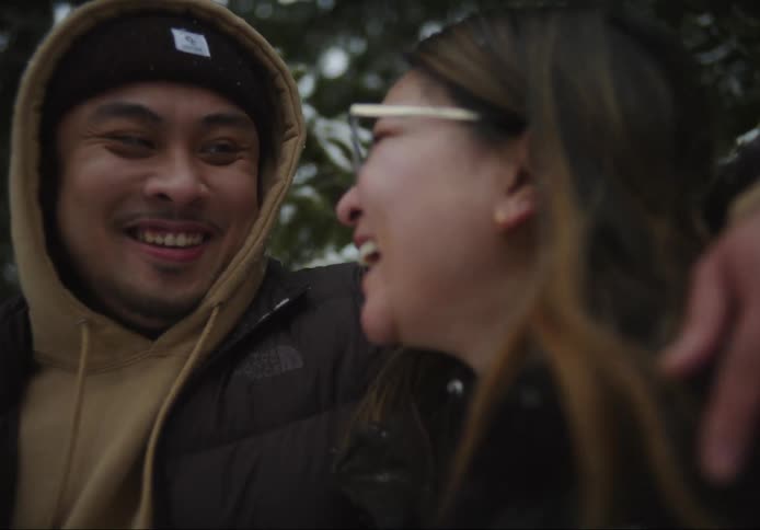 Biracial couple talking and smiling outdoors in the snow during day time