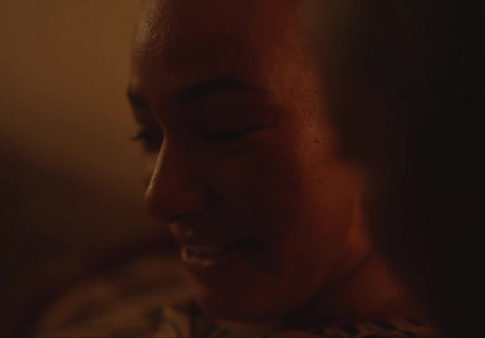 Two womens faces talking and smiling in a dimly lit indoor setting