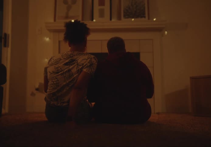 Two women sitting side by side on the floor in front of a fireplace