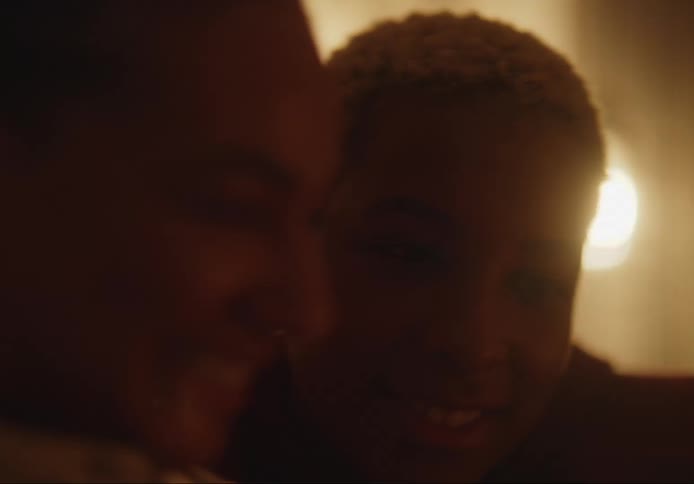Close up of a woman and an androgynous persons face indoors chatting and smiling