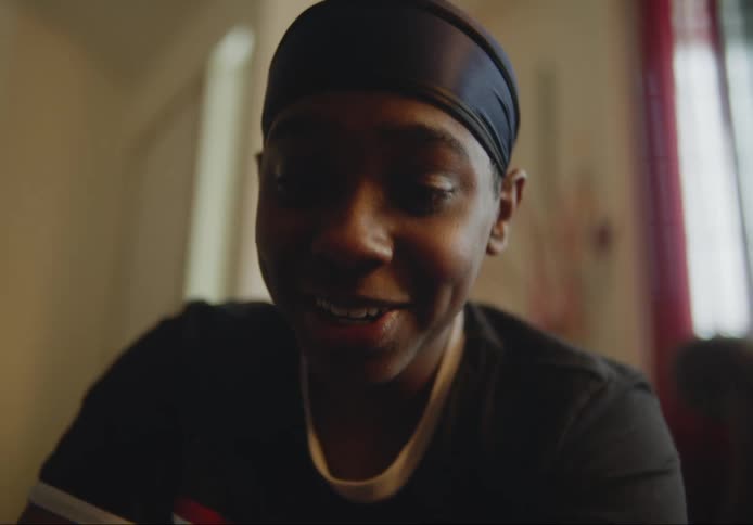 Close up of a persons face as they sit smiling indoors during the day