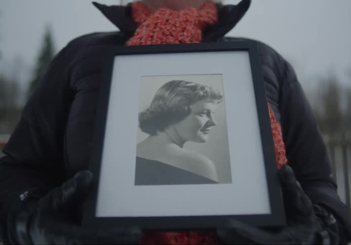 A person holding a black and white photograph of a woman
