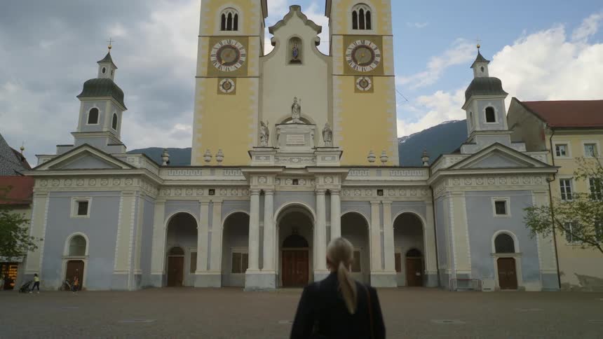 Woman walks toward a church building with arches